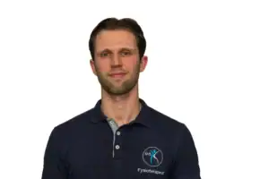 Profesjonell fysioterapeut i kolben, iført mørk blå polo med fysioterapeutlogo, står mot hvit bakgrunn, representerer helsetjenester og rehabilitering.