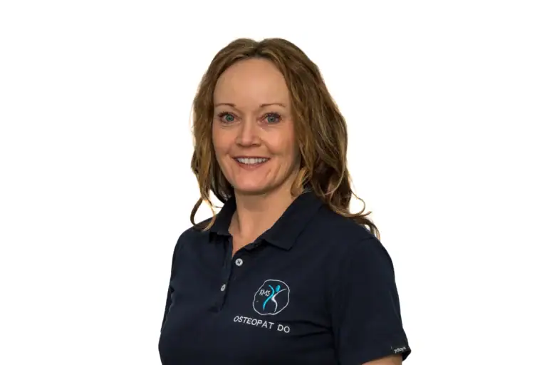 Kvinne i arbeidsantrekk med logo for osteopat, smilende og ser direkte mot kamera, representerer profesjonell helsepersonell innen kiropraktikk og osteopati.